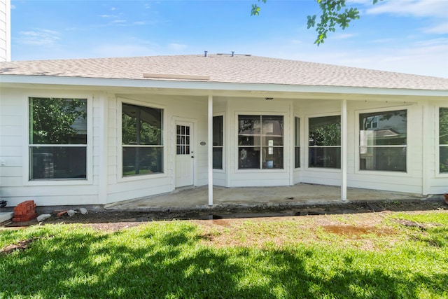 back of property with a lawn, roof with shingles, and a patio area
