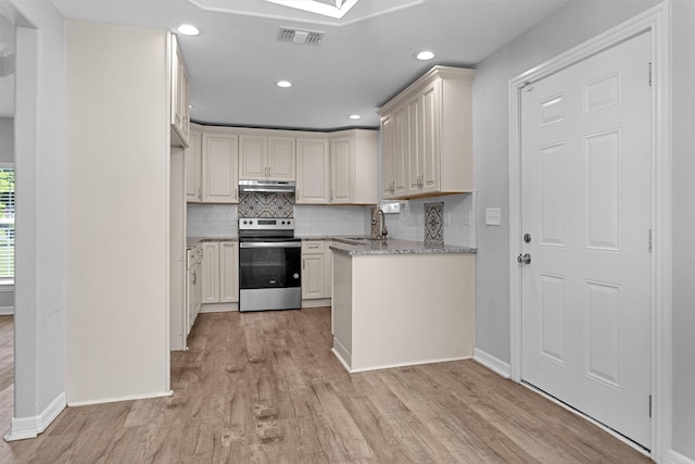 1107 Cypress St, Diboll, TX 75941 - kitchen with stainless steel range with electric cooktop, under cabinet range hood, light wood finished floors, backsplash, and baseboards