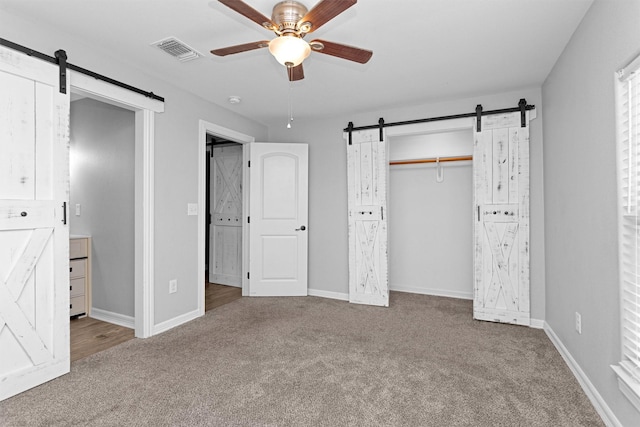 1107 Cypress St, Diboll, TX 75941 - unfurnished bedroom featuring a barn door, carpet flooring, and baseboards