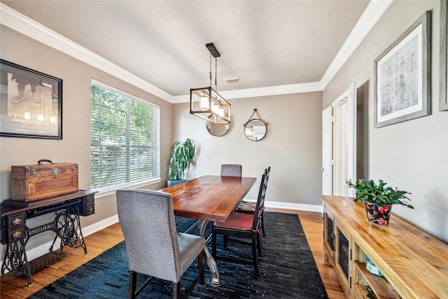 dining area with wood finished floors, crown molding, and baseboards