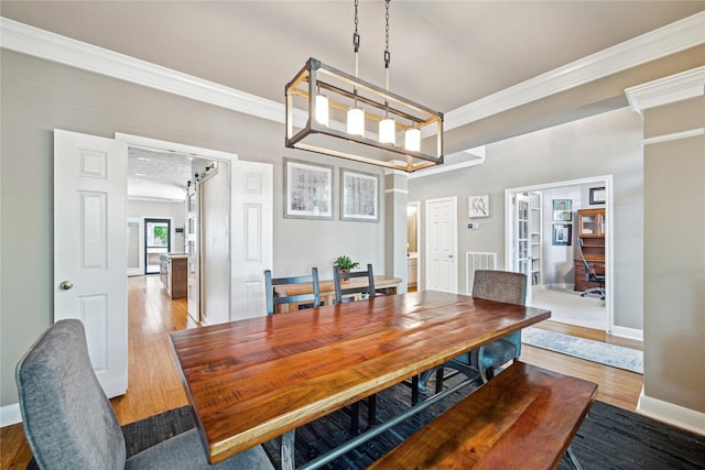 dining space featuring light wood-style flooring, crown molding, and baseboards