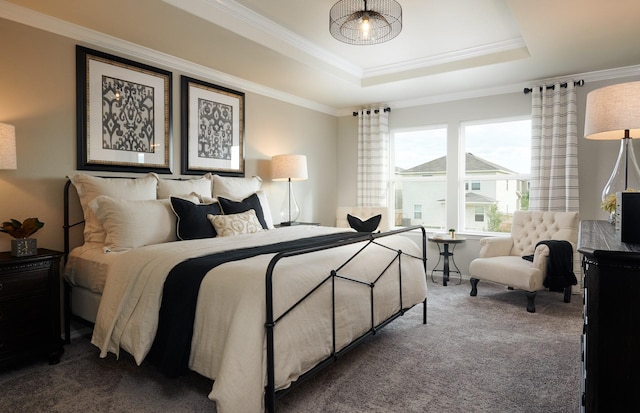 carpeted bedroom with ornamental molding and a tray ceiling