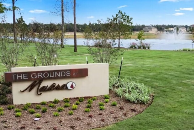 community / neighborhood sign featuring a water view and a yard