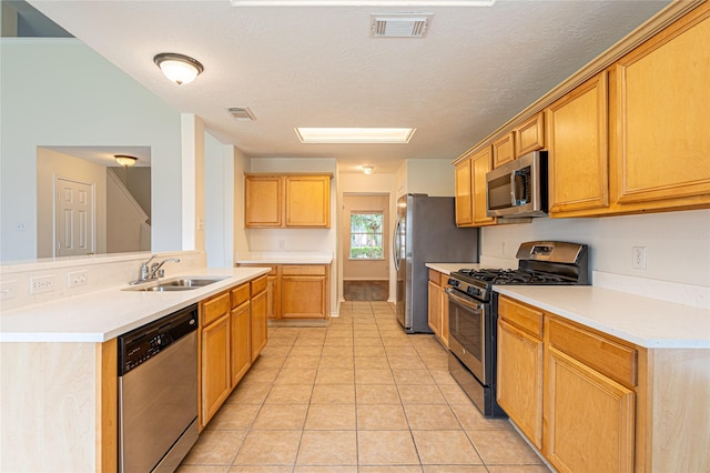 kitchen with stainless steel appliances, a sink, light tile patterned floors, light countertops, and a textured ceiling