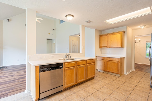 kitchen with stainless steel appliances, a sink, light countertops, a textured ceiling, and light tile patterned floors