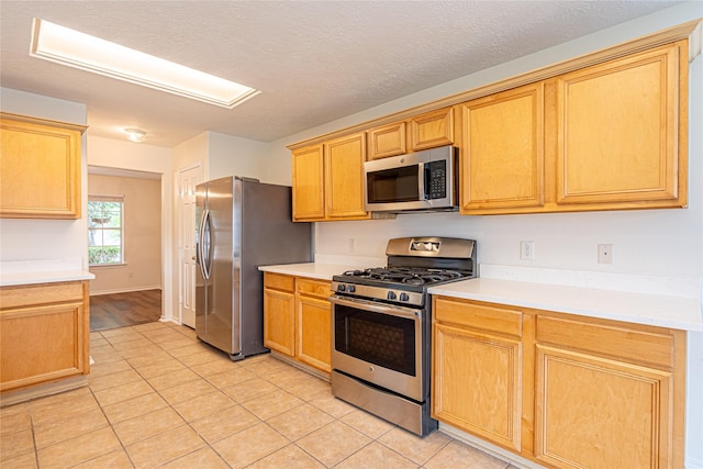 kitchen with appliances with stainless steel finishes, light tile patterned floors, and light countertops