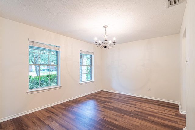 spare room featuring a chandelier, dark wood finished floors, baseboards, and a textured ceiling
