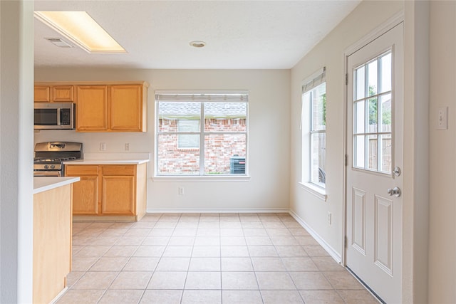 kitchen with stainless steel appliances, light countertops, light tile patterned floors, and baseboards