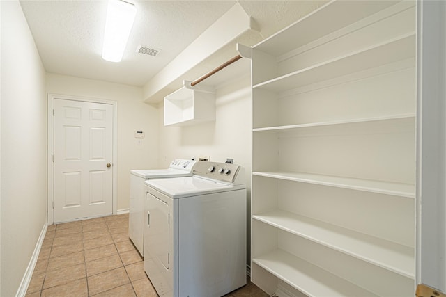 washroom featuring separate washer and dryer, baseboards, light tile patterned flooring, and a textured ceiling