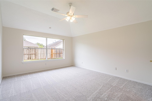 empty room with light colored carpet, ceiling fan, baseboards, and vaulted ceiling
