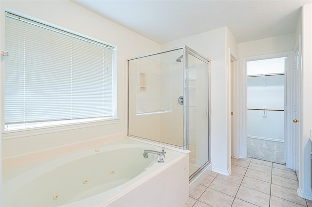 bathroom with a shower stall, tile patterned flooring, a whirlpool tub, a walk in closet, and baseboards