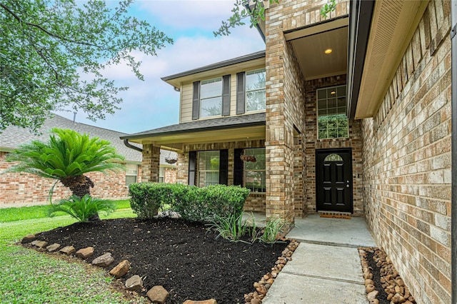 doorway to property with brick siding and covered porch