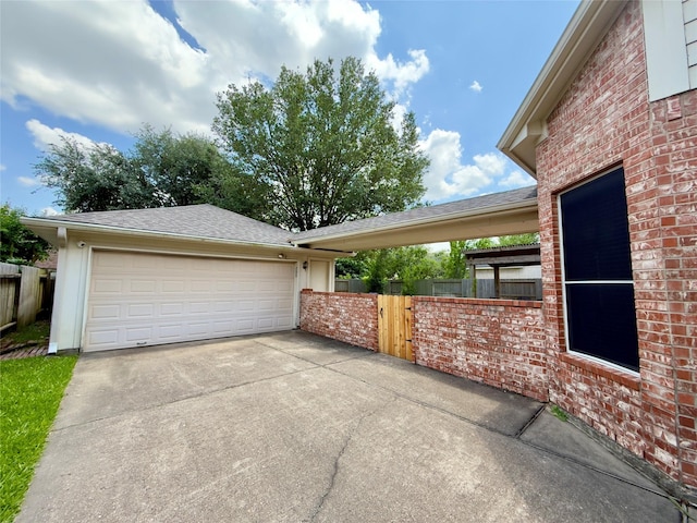 view of side of home featuring concrete driveway, a garage, fence, and brick siding