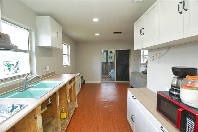 26643 Carol Ln, Splendora, TX 77372 - kitchen with a sink, light countertops, light wood-style flooring, recessed lighting, and white cabinets