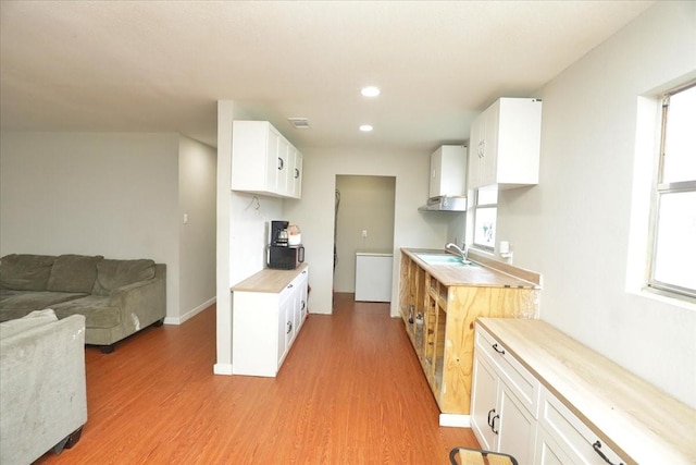 26643 Carol Ln, Splendora, TX 77372 - kitchen featuring a sink, light wood-style floors, light countertops, open floor plan, and white cabinetry