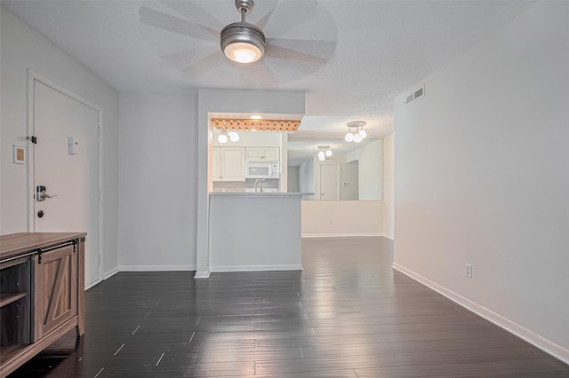 1900 Bay Area Blvd Unit 184, Houston, TX 77058 - unfurnished living room featuring ceiling fan, dark wood-style flooring, baseboards, and a textured ceiling