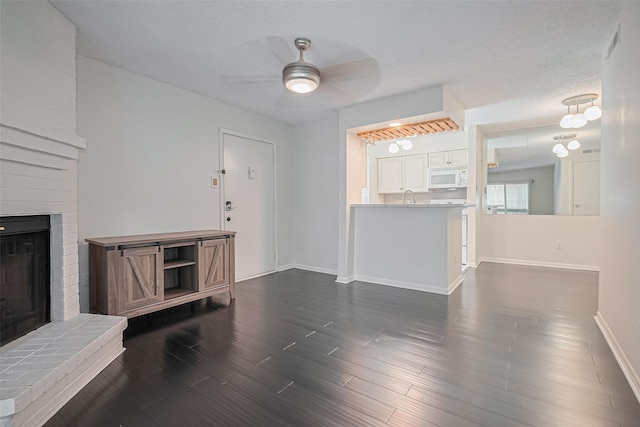 1900 Bay Area Blvd Unit 184, Houston, TX 77058 - unfurnished living room featuring a ceiling fan, a fireplace, baseboards, dark wood-style floors, and a sink