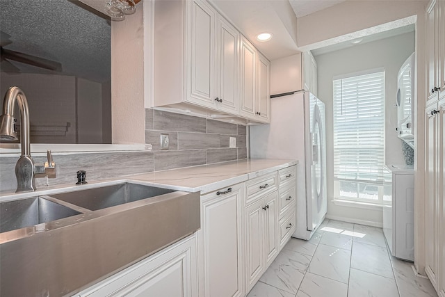 1900 Bay Area Blvd Unit 184, Houston, TX 77058 - kitchen with a sink, light marble finish floors, decorative backsplash, ceiling fan, and light countertops