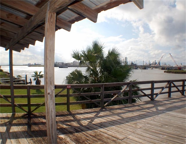 wooden deck with a water view and a lawn