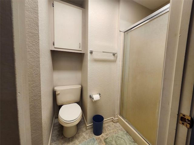 full bath with a shower stall, toilet, a textured wall, baseboards, and tile patterned floors