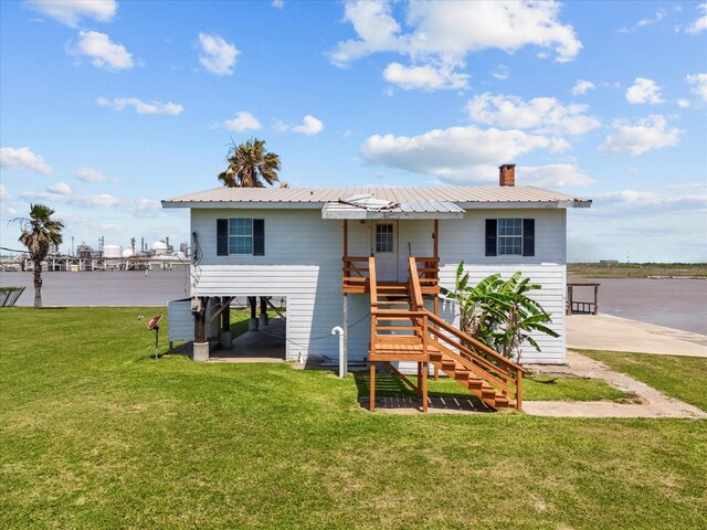 1134 Canal Dr, Surfside Beach, TX 77541 - back of house with stairway, a metal roof, a chimney, and a lawn