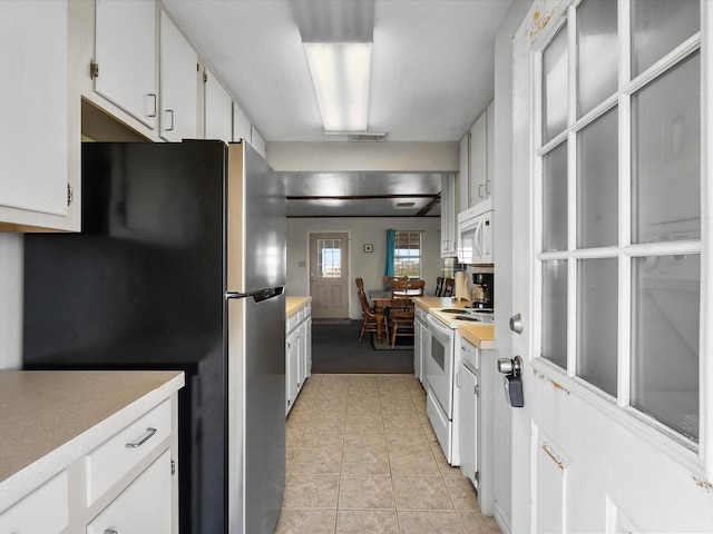 1134 Canal Dr, Surfside Beach, TX 77541 - kitchen with white appliances, light countertops, white cabinetry, and light tile patterned flooring