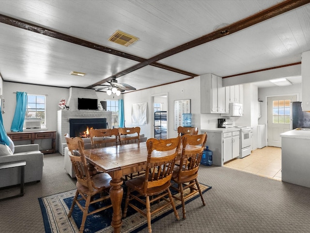 1134 Canal Dr, Surfside Beach, TX 77541 - dining room featuring a fireplace, beamed ceiling, a ceiling fan, and light carpet
