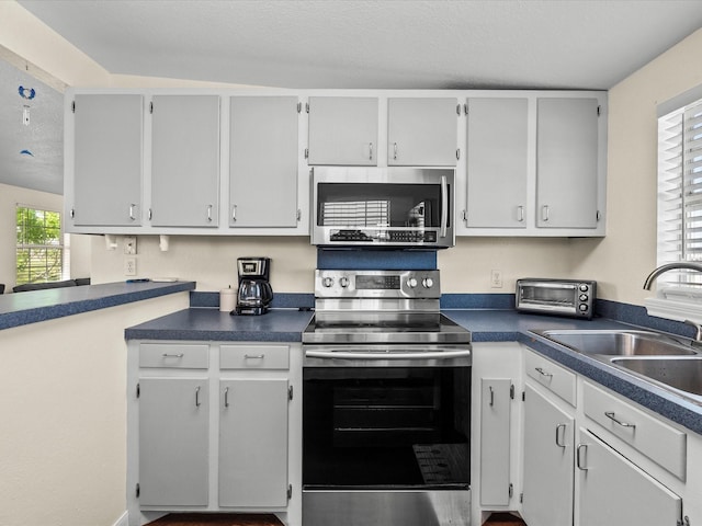 1134 Canal Dr, Surfside Beach, TX 77541 - kitchen with appliances with stainless steel finishes, dark countertops, and a textured ceiling