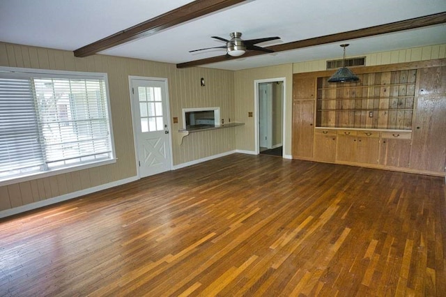 524 Oak Dr, Lake Jackson, TX 77566 - unfurnished living room with wood finished floors, beamed ceiling, wooden walls, ceiling fan, and baseboards