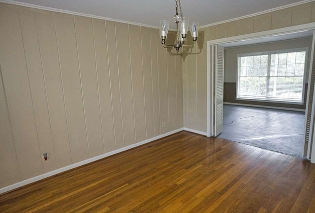 524 Oak Dr, Lake Jackson, TX 77566 - unfurnished room with a chandelier, dark wood finished floors, crown molding, baseboards, and wood walls
