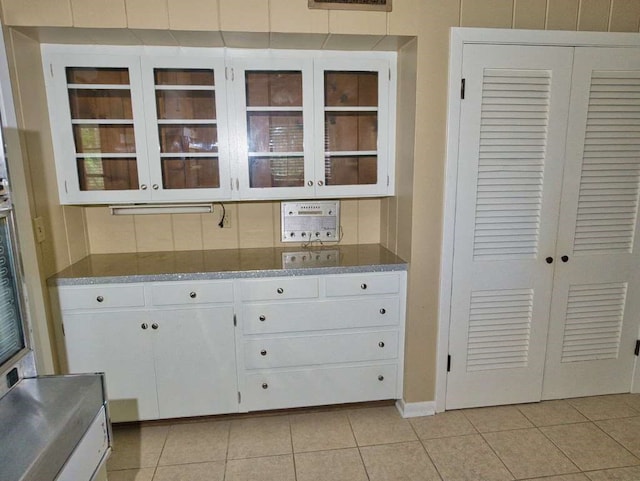 524 Oak Dr, Lake Jackson, TX 77566 - kitchen featuring light tile patterned floors, white cabinets, glass insert cabinets, stone countertops, and baseboards