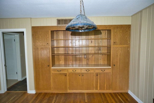 524 Oak Dr, Lake Jackson, TX 77566 - unfurnished dining area with dark wood-style flooring, wood walls, baseboards, and a textured ceiling