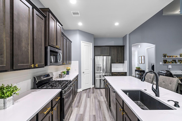 4302 Stoney Heights Ct, Spring, TX 77388 - kitchen featuring appliances with stainless steel finishes, a sink, arched walkways, dark brown cabinets, and backsplash