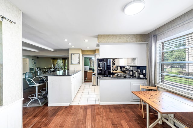 12726 Pebblebrook Dr, Houston, TX 77024 - kitchen featuring a peninsula, dark countertops, healthy amount of natural light, light wood-type flooring, and recessed lighting