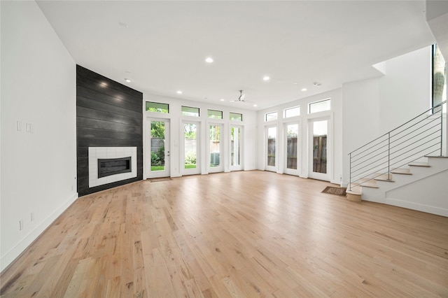 unfurnished living room with recessed lighting, a large fireplace, light wood-style floors, stairs, and baseboards