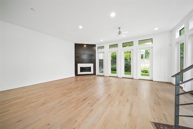 unfurnished living room with a fireplace, recessed lighting, stairs, light wood-style flooring, and a ceiling fan