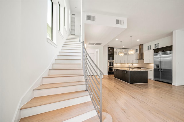 stairs with wood finished floors, recessed lighting, and baseboards