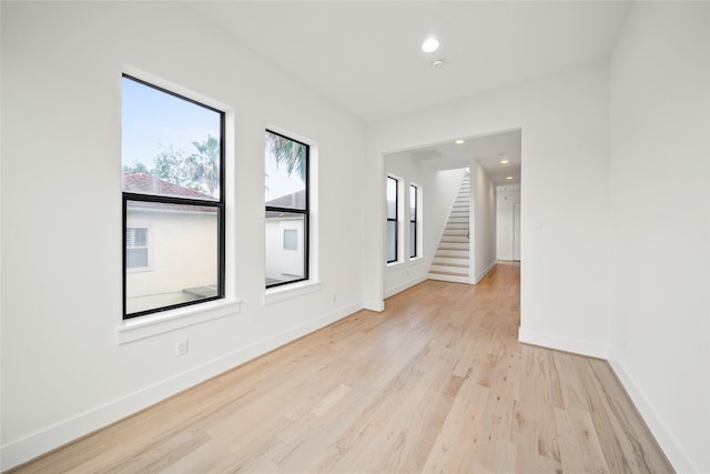 unfurnished room featuring light wood-style floors, baseboards, stairs, and recessed lighting
