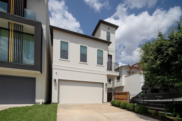 contemporary home with stucco siding, a garage, fence, and driveway