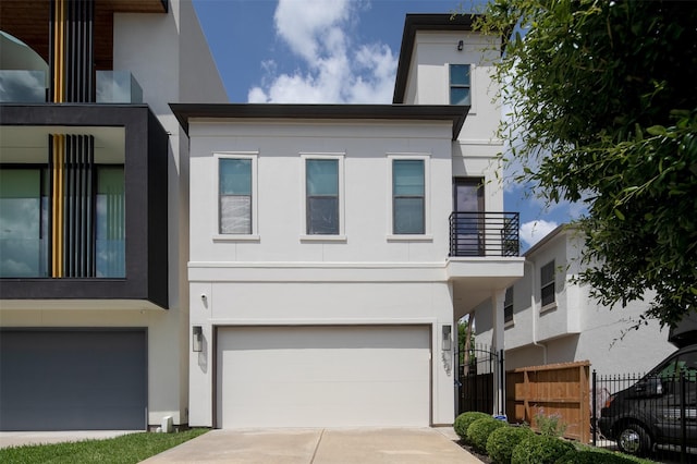 modern home featuring stucco siding, an attached garage, and a balcony