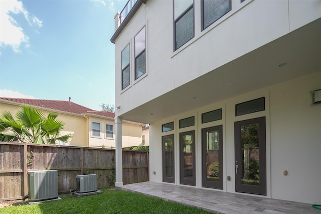 rear view of property with central AC unit, stucco siding, fence, and a patio