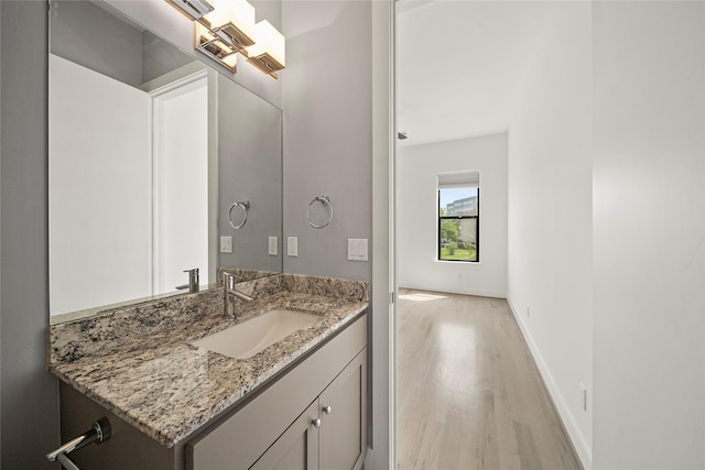 bathroom with wood finished floors, vanity, and baseboards