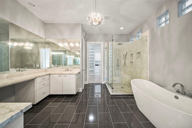 bathroom featuring a shower stall, a chandelier, vanity, and a freestanding bath