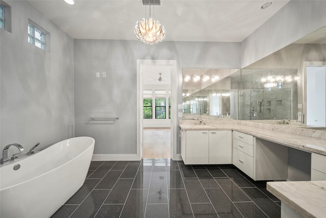 bathroom featuring baseboards, a soaking tub, vanity, granite tiled floors, and a chandelier