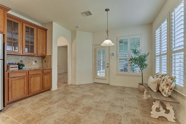 71 Ginger Jar St, The Woodlands, TX 77382 - kitchen with arched walkways, brown cabinets, backsplash, and healthy amount of natural light