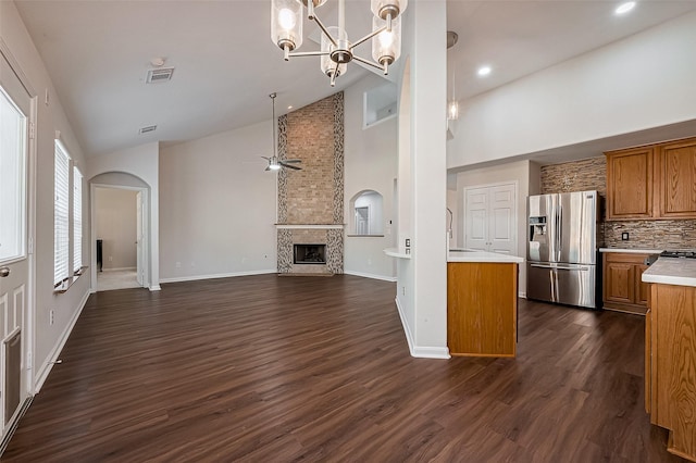 18314 Madisons Crossing Ln, Tomball, TX 77375 - kitchen featuring stainless steel fridge, brown cabinetry, light countertops, arched walkways, and a fireplace