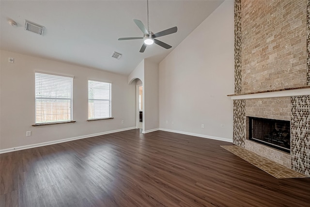18314 Madisons Crossing Ln, Tomball, TX 77375 - unfurnished living room with a ceiling fan, high vaulted ceiling, arched walkways, dark wood-type flooring, and a fireplace