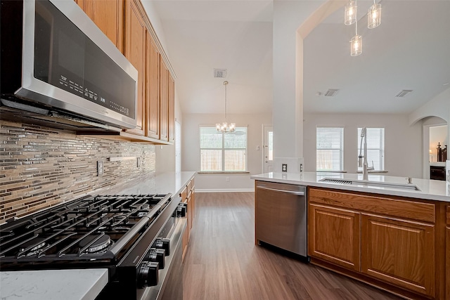 18314 Madisons Crossing Ln, Tomball, TX 77375 - kitchen with appliances with stainless steel finishes, arched walkways, dark wood finished floors, light countertops, and backsplash