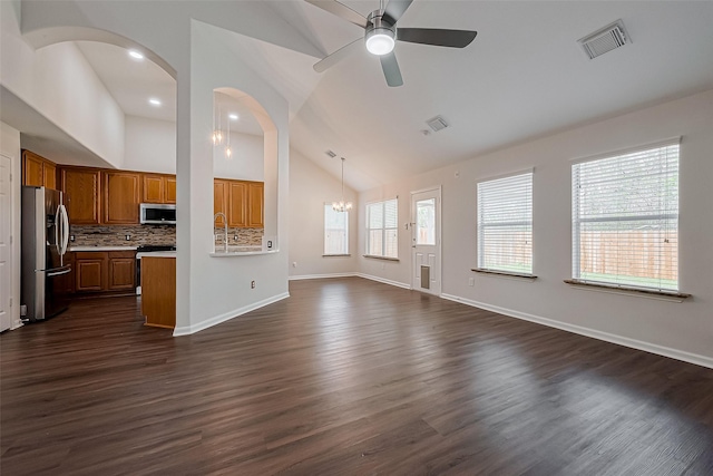 18314 Madisons Crossing Ln, Tomball, TX 77375 - unfurnished living room with ceiling fan, baseboards, dark wood-style flooring, arched walkways, and high vaulted ceiling