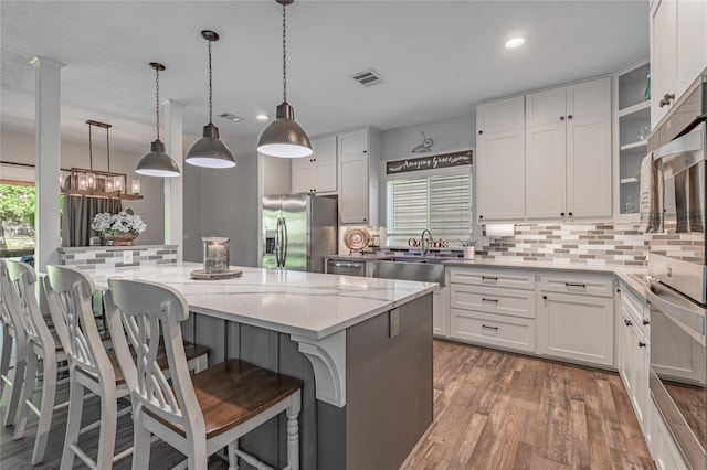 16 Wildwood Lake Dr, Huntsville, TX 77340 - kitchen with appliances with stainless steel finishes, tasteful backsplash, white cabinetry, light wood finished floors, and light stone counters
